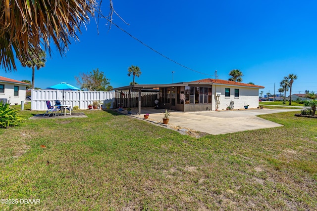 rear view of house featuring a patio, a lawn, and fence