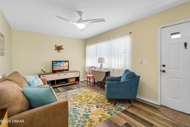 living room with ceiling fan, baseboards, and wood finished floors