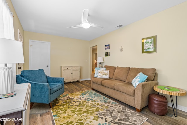 living room with ceiling fan, visible vents, baseboards, and wood finished floors