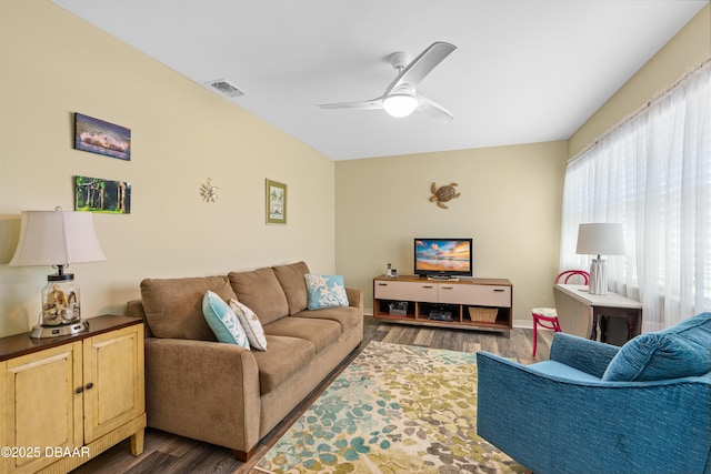 living room with dark wood finished floors, baseboards, visible vents, and ceiling fan