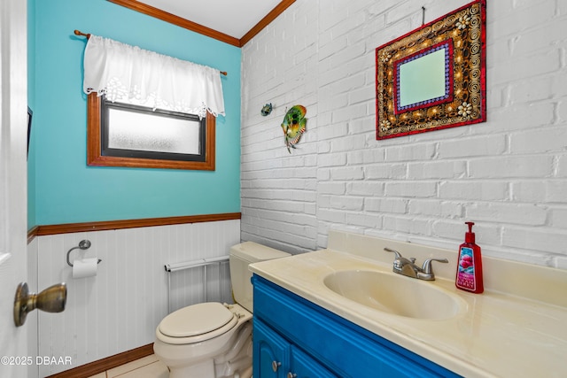 bathroom featuring toilet, brick wall, wainscoting, and ornamental molding