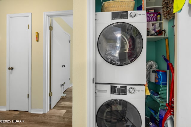 washroom featuring laundry area, stacked washer and dryer, and wood finished floors