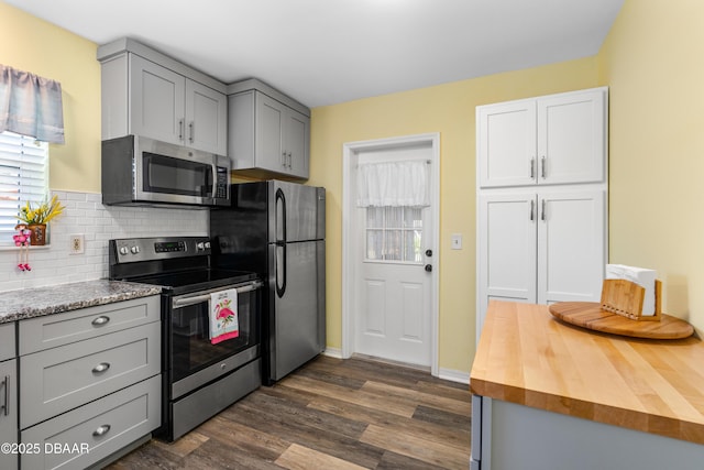 kitchen with wooden counters, dark wood-style flooring, appliances with stainless steel finishes, and gray cabinetry