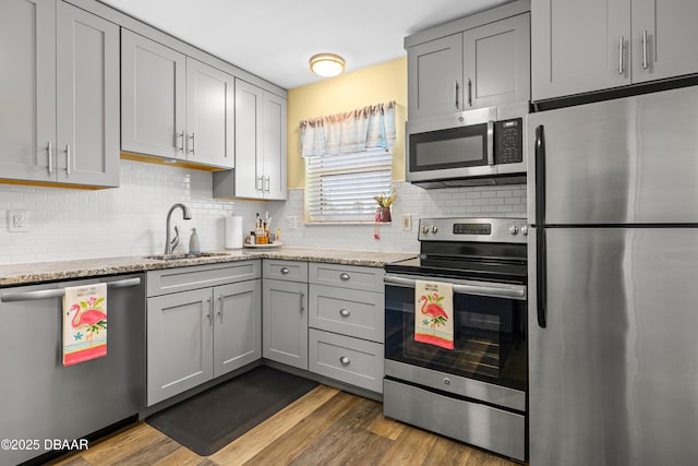 kitchen featuring a sink, appliances with stainless steel finishes, wood finished floors, and gray cabinetry