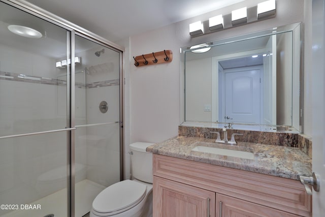 bathroom featuring vanity, toilet, and a shower with door