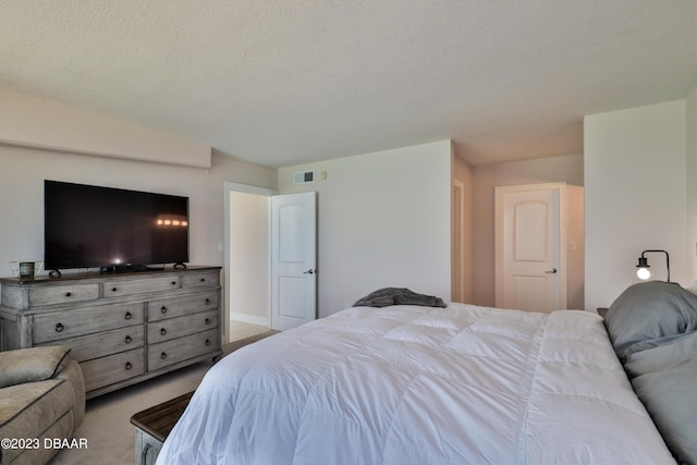 bedroom featuring light carpet and a textured ceiling