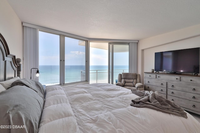 bedroom featuring floor to ceiling windows, access to exterior, and a textured ceiling