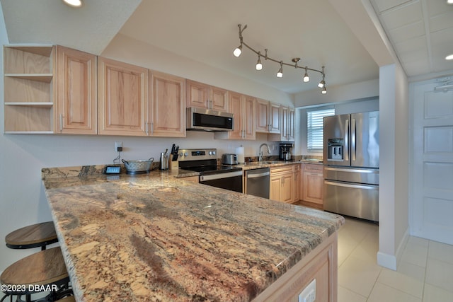 kitchen featuring sink, kitchen peninsula, stainless steel appliances, light stone countertops, and light brown cabinets