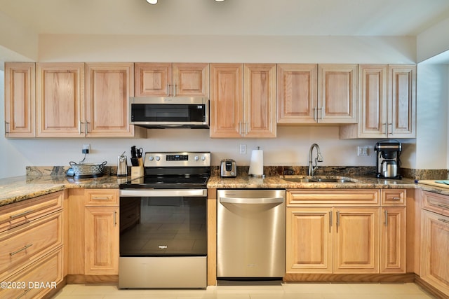 kitchen featuring dark stone countertops, sink, light brown cabinetry, and appliances with stainless steel finishes