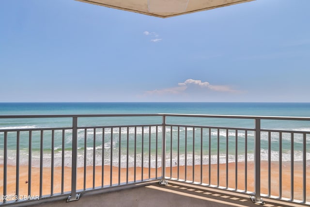 balcony with a water view and a view of the beach