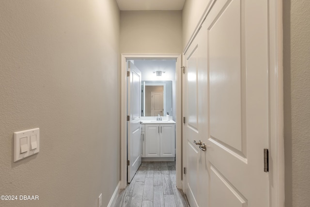 corridor with sink and light hardwood / wood-style flooring