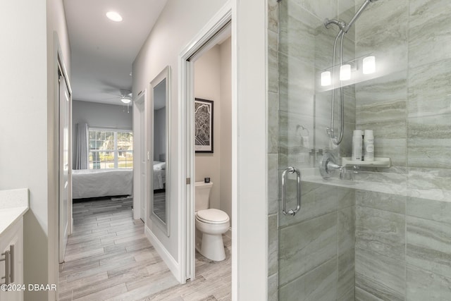 bathroom with vanity, a shower with door, ceiling fan, toilet, and wood-type flooring