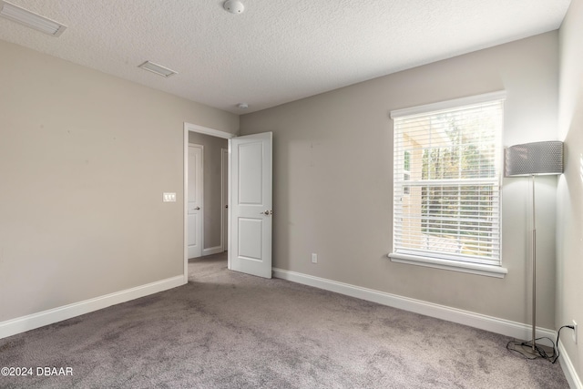 unfurnished bedroom featuring carpet floors, a textured ceiling, and multiple windows