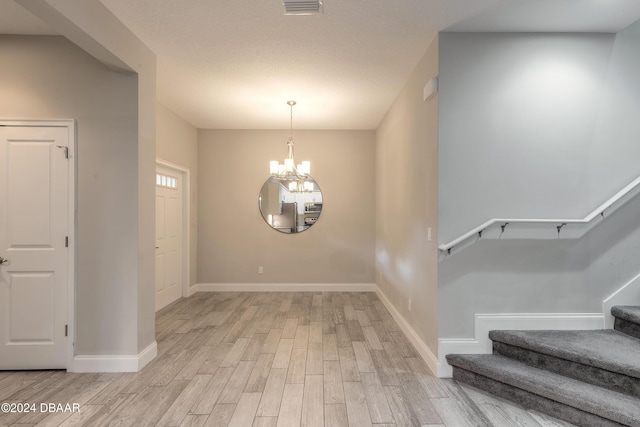 entryway with light hardwood / wood-style floors and a chandelier