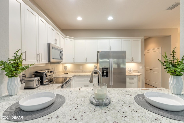 kitchen with sink, light stone counters, white cabinetry, and stainless steel appliances