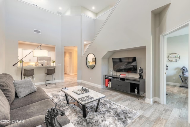 living room with a towering ceiling and light hardwood / wood-style flooring