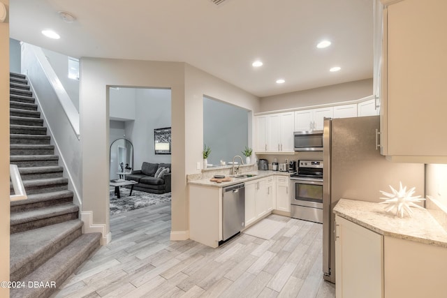 kitchen featuring white cabinetry, sink, appliances with stainless steel finishes, and light hardwood / wood-style flooring