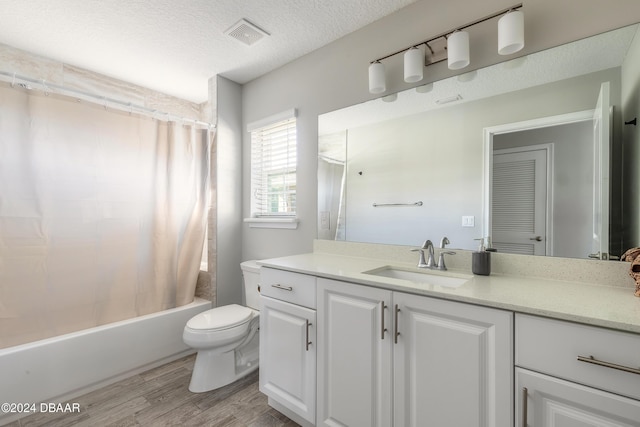 full bathroom with shower / bath combination with curtain, vanity, a textured ceiling, wood-type flooring, and toilet