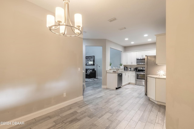 kitchen featuring pendant lighting, white cabinets, stainless steel appliances, and light hardwood / wood-style flooring