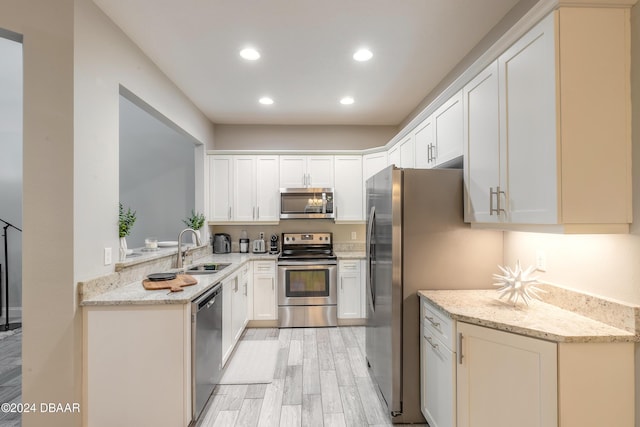 kitchen with light stone counters, white cabinetry, sink, and appliances with stainless steel finishes