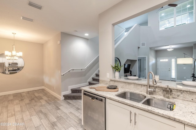 kitchen with white cabinetry, dishwasher, sink, light stone counters, and light wood-type flooring