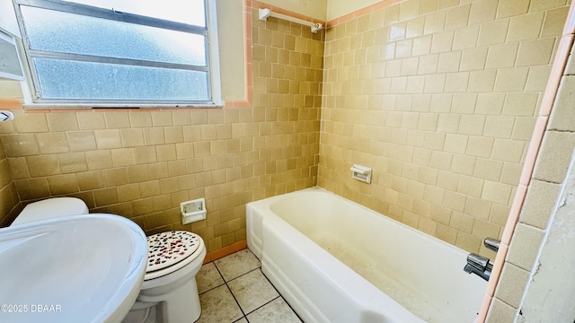 bathroom featuring tile patterned floors, toilet, sink, and tile walls