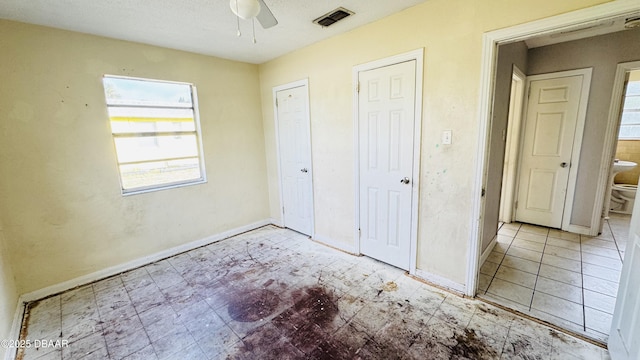 unfurnished bedroom featuring multiple closets and ceiling fan