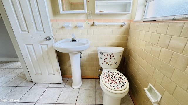 bathroom with toilet, tile patterned flooring, and tile walls