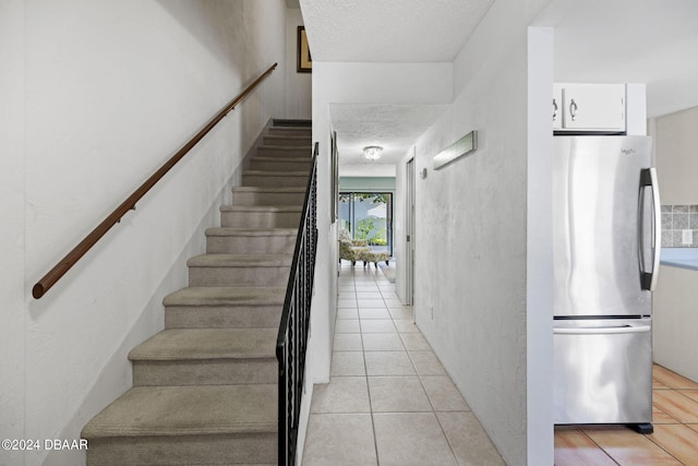 staircase with tile patterned flooring and a textured ceiling