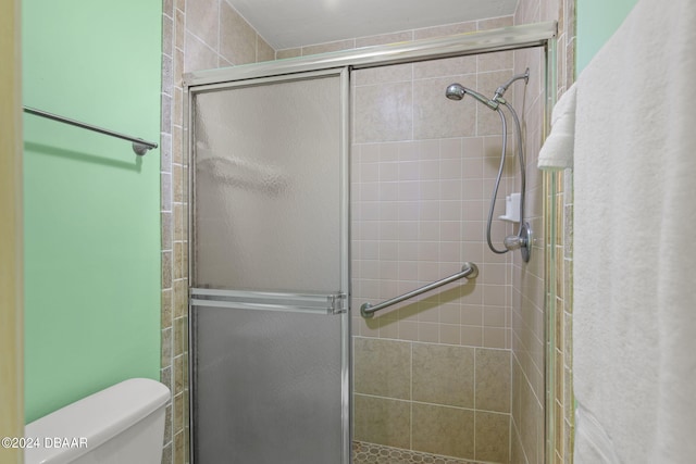 bathroom featuring a shower with shower door and toilet