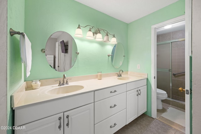 bathroom with vanity, toilet, a shower with shower door, and tile patterned flooring