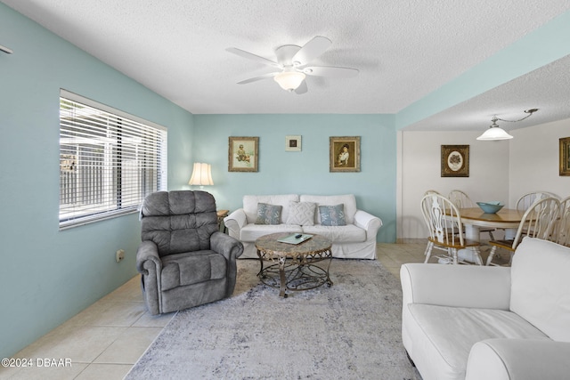 living room with a textured ceiling, ceiling fan, and light tile patterned flooring