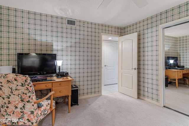 carpeted office featuring a ceiling fan, a textured ceiling, visible vents, and wallpapered walls