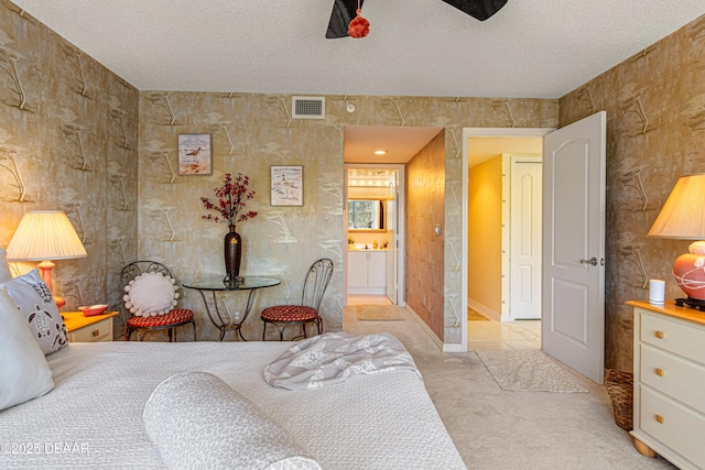 bedroom with visible vents, carpet floors, baseboards, a textured ceiling, and ensuite bath