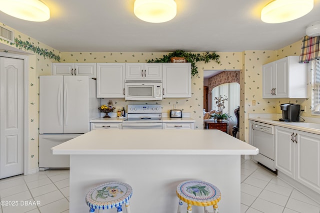 kitchen with white appliances, wallpapered walls, light tile patterned floors, and light countertops