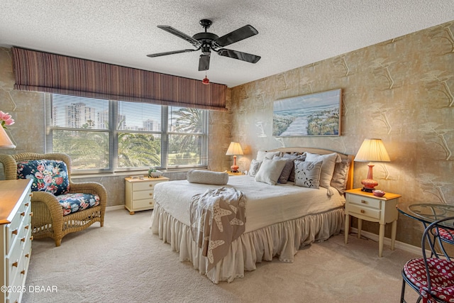 bedroom with baseboards, a ceiling fan, a textured ceiling, and light carpet