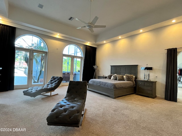 carpeted bedroom with access to outside, ceiling fan, and a high ceiling