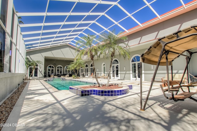 view of swimming pool featuring glass enclosure, a patio, a hot tub, and french doors