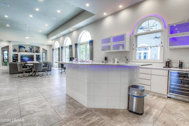 2540 Taxiway Echo, Port Orange, FL 32128 - kitchen featuring beverage cooler, a ceiling fan, white cabinets, a towering ceiling, and light countertops