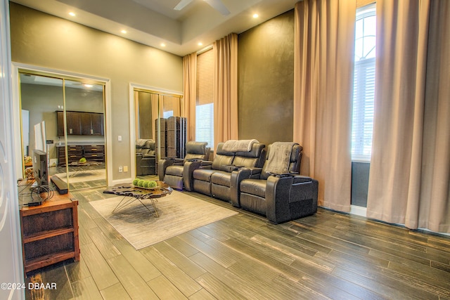 living room with ceiling fan, a high ceiling, and wood-type flooring