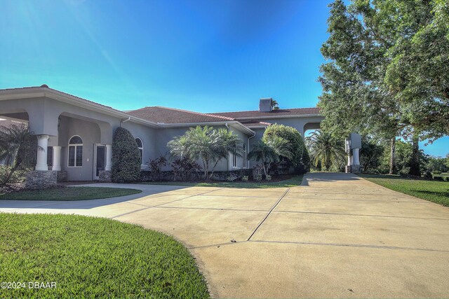 2540 Taxiway Echo, Port Orange, FL 32128 - view of front of home featuring stucco siding, curved driveway, a chimney, and a front yard