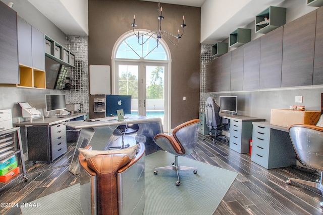 office space featuring a towering ceiling, french doors, dark hardwood / wood-style flooring, and a notable chandelier