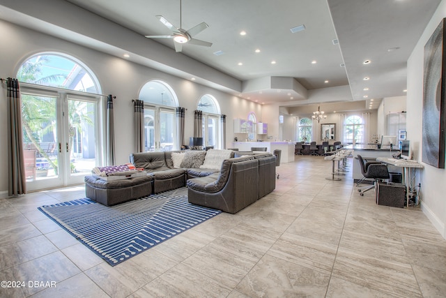 living room with ceiling fan with notable chandelier, a healthy amount of sunlight, and french doors