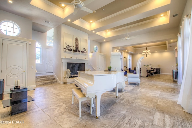 miscellaneous room with a high ceiling, a raised ceiling, ornamental molding, and ceiling fan with notable chandelier