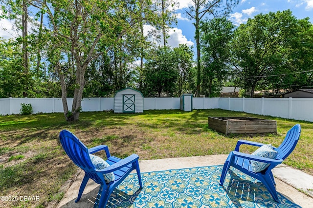 view of yard featuring a vegetable garden, a fenced backyard, a storage shed, an outbuilding, and a patio