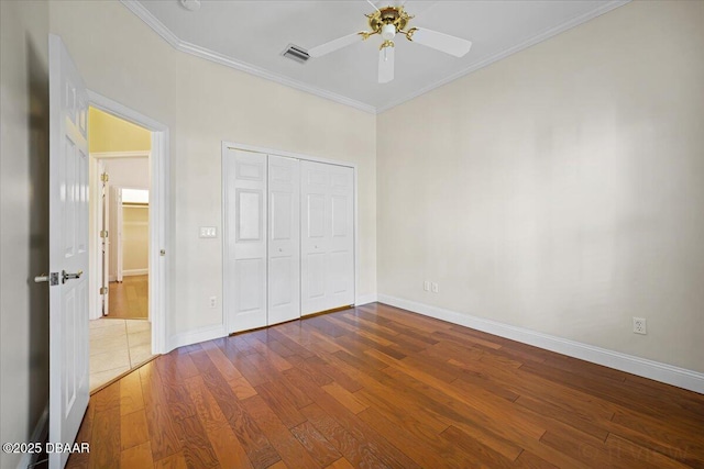 unfurnished bedroom with wood-type flooring, ceiling fan, crown molding, and a closet