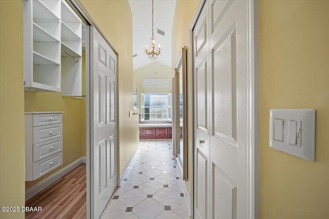 hallway with lofted ceiling and a chandelier