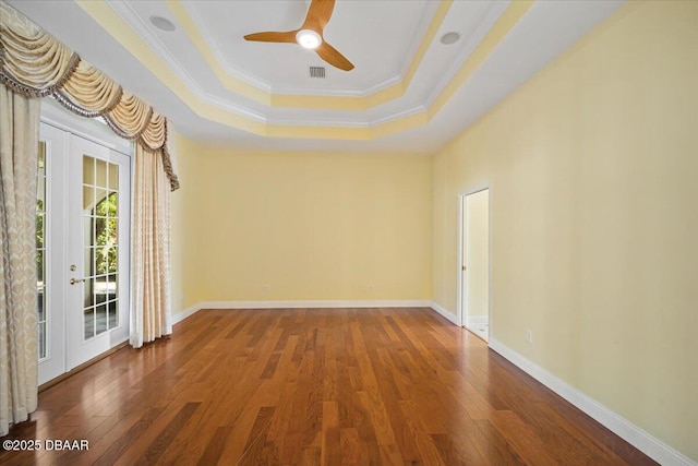 unfurnished room with crown molding, hardwood / wood-style floors, a tray ceiling, and french doors