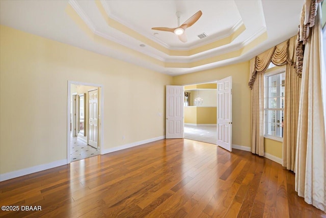 spare room featuring hardwood / wood-style flooring, ceiling fan, crown molding, and a raised ceiling