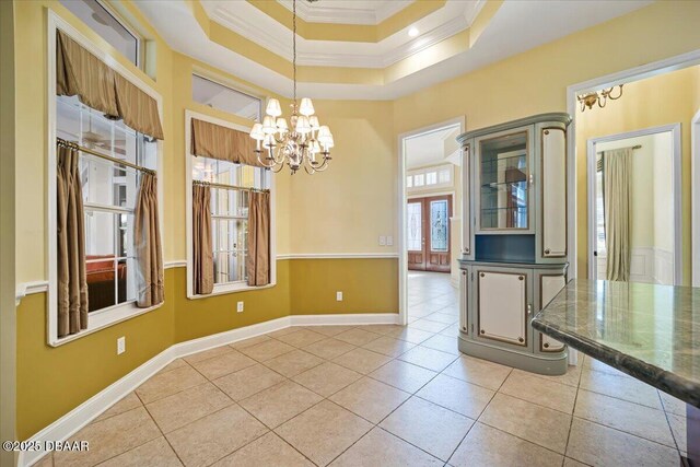 unfurnished room featuring ornamental molding, light tile patterned flooring, an inviting chandelier, and a tray ceiling